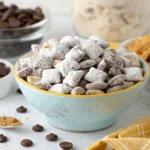 Bowl of perfectly coated Muddy Buddies with powdered sugar, showing how to avoid sogginess.