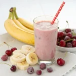 Vibrant banana cherry smoothie with fresh banana slices and frozen cherries on a white background