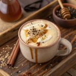 Creamy tahini latte in ceramic mug with honey drizzle and sesame seeds on a rustic tray