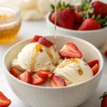 Creamy cottage cheese protein ice cream topped with strawberries and honey in a bowl