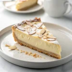 Slice of Almond Ricotta Cheesecake Pie on a white plate, creamy ricotta filling with almond flour crust and powdered sugar topping.